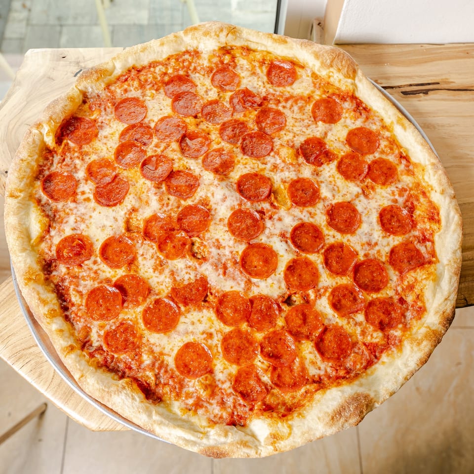 Large pepperoni pizza with melted cheese and a golden crust on a wooden table.